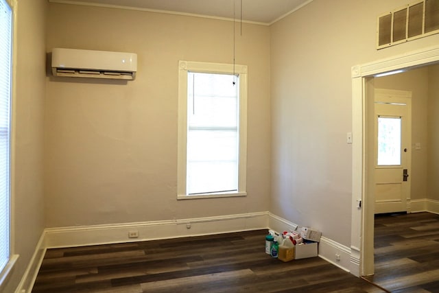 empty room featuring a healthy amount of sunlight, dark hardwood / wood-style flooring, and a wall mounted AC