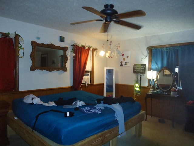 carpeted bedroom with ceiling fan, cooling unit, a textured ceiling, and wood walls