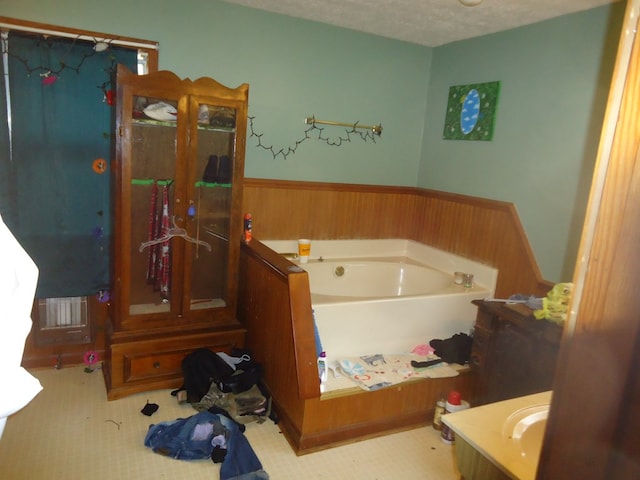 bathroom featuring vanity, a washtub, and a textured ceiling