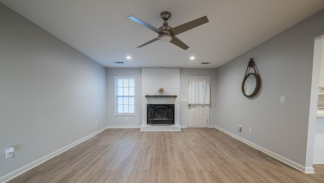 unfurnished living room featuring baseboards, ceiling fan, a fireplace, and light wood-style floors