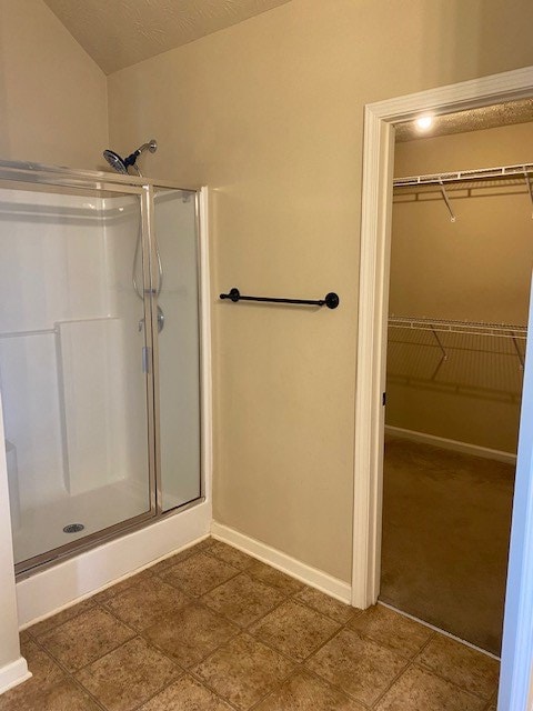 bathroom with a shower with shower door and a textured ceiling