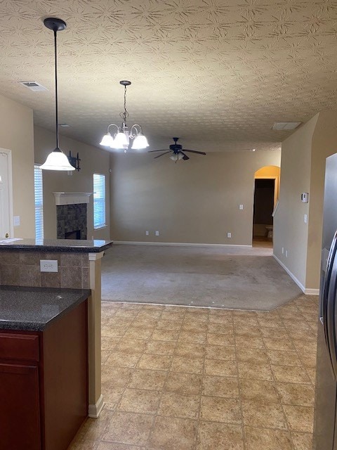 kitchen featuring ceiling fan, hanging light fixtures, a textured ceiling, and stainless steel refrigerator