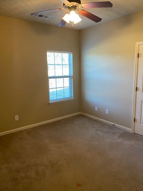 carpeted empty room with a textured ceiling and ceiling fan