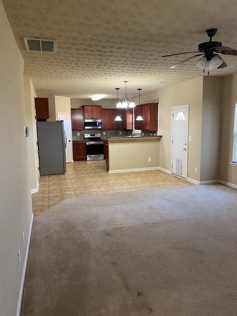 kitchen with ceiling fan with notable chandelier, appliances with stainless steel finishes, backsplash, hanging light fixtures, and kitchen peninsula