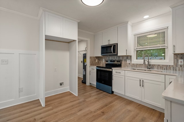 919 54th St, Columbus, GA 31904 - kitchen with stainless steel microwave, range with electric stovetop, ornamental molding, white cabinets, and backsplash