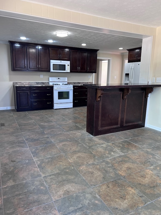 4517 Sherwood Ave, Columbus, GA 31904 - kitchen with white appliances, a kitchen bar, dark brown cabinetry, recessed lighting, and dark stone finish flooring