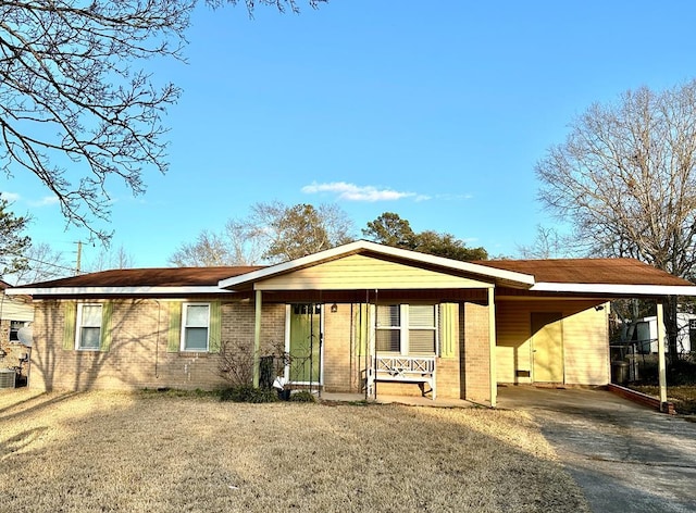 ranch-style home with brick siding, covered porch, an attached carport, driveway, and a front lawn