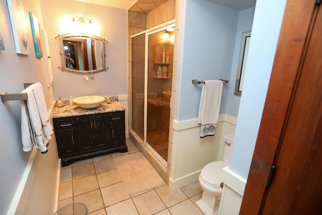 bathroom with tile patterned flooring, a shower with door, vanity, and toilet