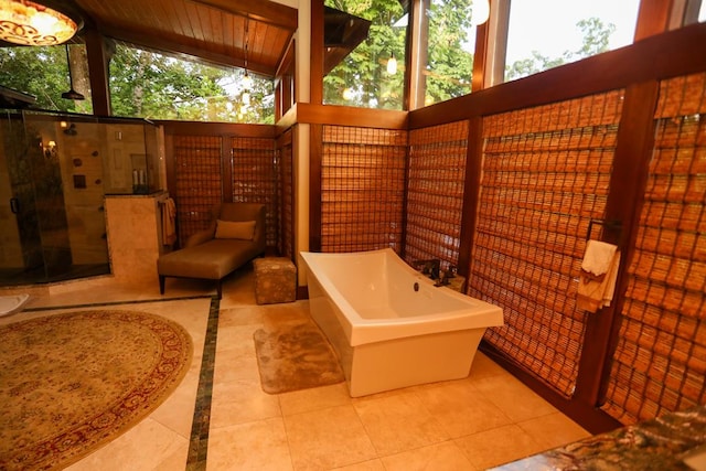 bathroom with tile patterned floors, a bathing tub, plenty of natural light, and high vaulted ceiling