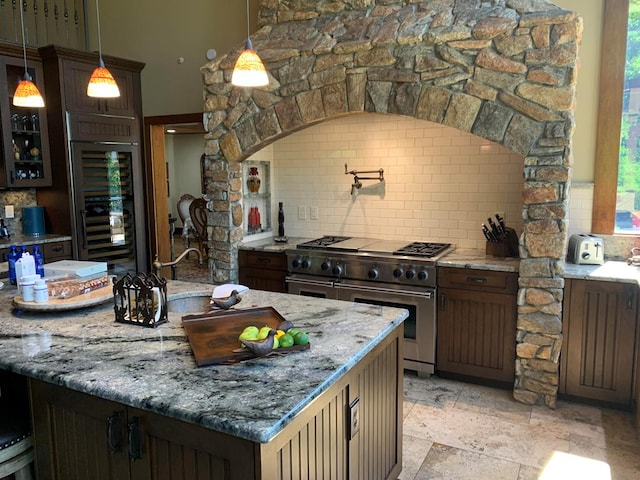 kitchen featuring decorative backsplash, light stone counters, high end stainless steel range, wine cooler, and hanging light fixtures