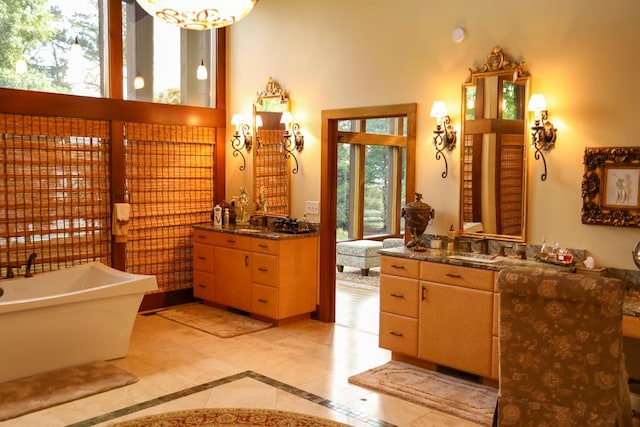 bathroom featuring a bathing tub, vanity, a towering ceiling, and tile patterned floors