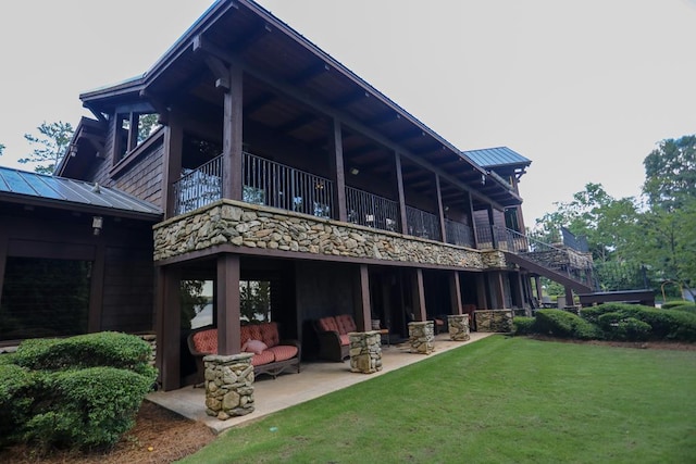 back of property featuring a lawn, a balcony, and a patio