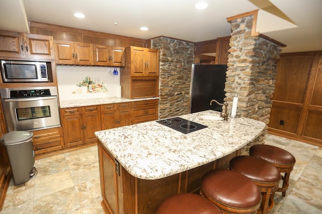 kitchen with light stone countertops, a kitchen island with sink, and appliances with stainless steel finishes