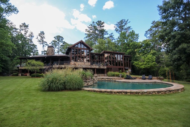 rear view of property featuring a pool side deck and a yard