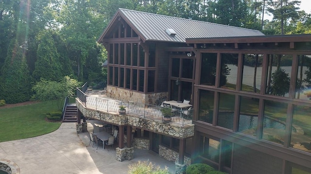 wooden terrace featuring a sunroom, a patio area, and a lawn