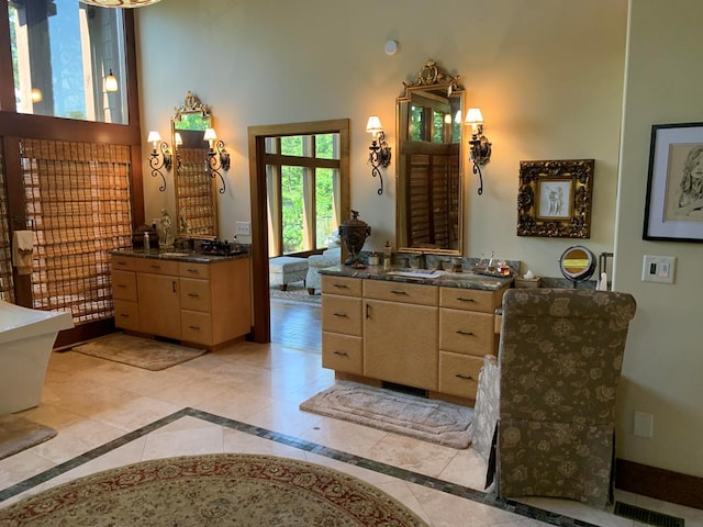 bathroom featuring tile patterned floors, vanity, and a towering ceiling