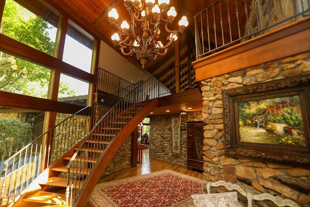 staircase with a chandelier, hardwood / wood-style floors, and high vaulted ceiling