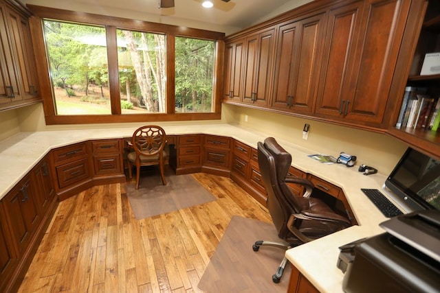 home office with built in desk and light hardwood / wood-style flooring