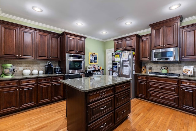 1811 Park Dr, Columbus, GA 31906 - kitchen featuring appliances with stainless steel finishes, ornamental molding, light wood finished floors, decorative backsplash, and dark stone counters
