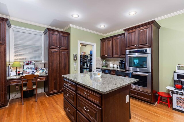 1811 Park Dr, Columbus, GA 31906 - kitchen with double oven, light wood finished floors, decorative backsplash, ornamental molding, and a center island