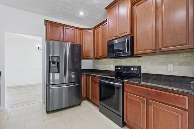 4685 Ivy Patch Dr, Fortson, GA 31808 - kitchen featuring stainless steel appliances, tasteful backsplash, dark stone countertops, a textured ceiling, and baseboards