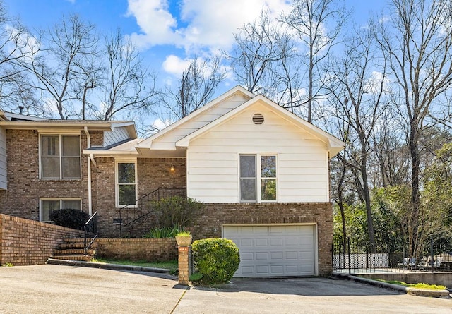 tri-level home featuring aphalt driveway, brick siding, crawl space, fence, and a garage