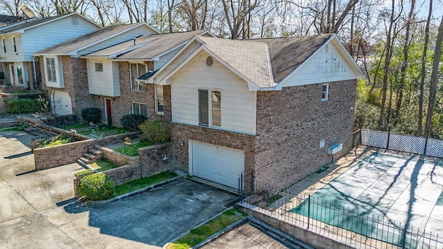 view of front of property with driveway, a garage, fence, and brick siding