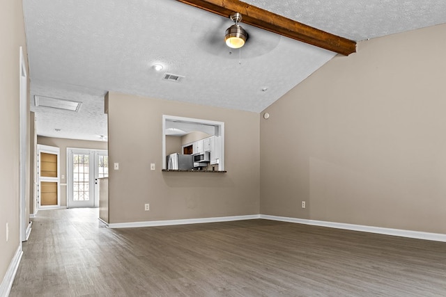 unfurnished living room with vaulted ceiling with beams, visible vents, a textured ceiling, wood finished floors, and baseboards