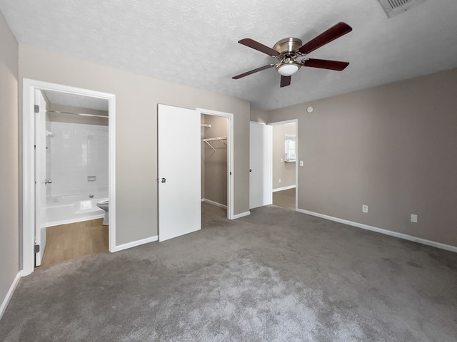 unfurnished bedroom with a closet, visible vents, a spacious closet, connected bathroom, and a textured ceiling