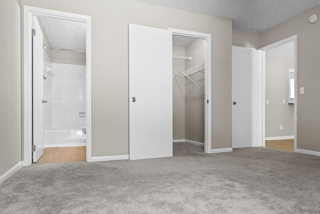 unfurnished bedroom featuring a textured ceiling, a closet, carpet, and baseboards