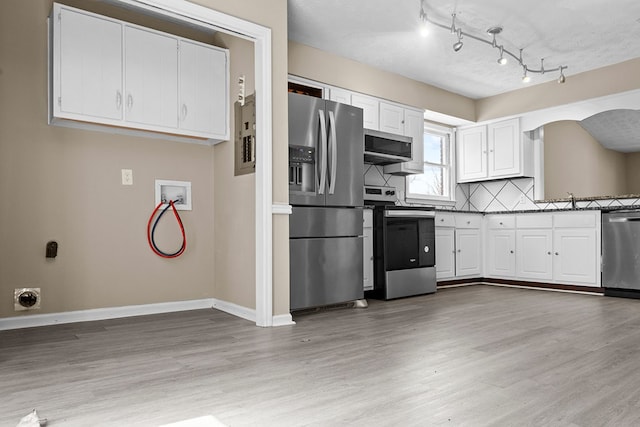 kitchen with tasteful backsplash, light wood-style flooring, appliances with stainless steel finishes, white cabinetry, and baseboards