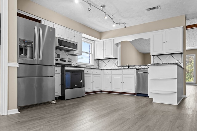 kitchen featuring appliances with stainless steel finishes, white cabinets, visible vents, and light wood-style flooring