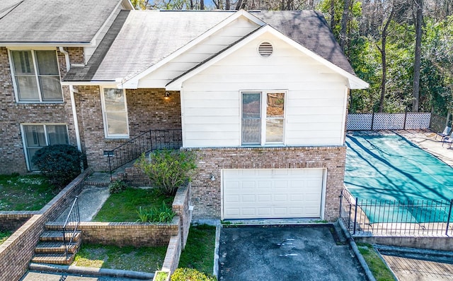 view of front facade with an attached garage, roof with shingles, stairway, and brick siding