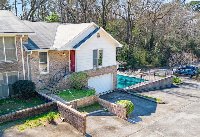 exterior space featuring brick siding, an attached garage, crawl space, fence, and driveway