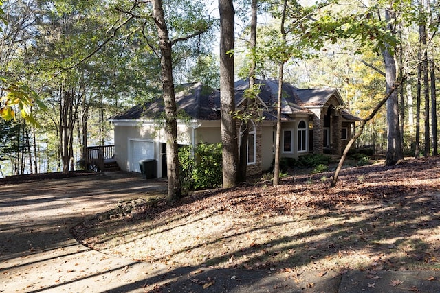 view of side of property with stucco siding, an attached garage, and dirt driveway