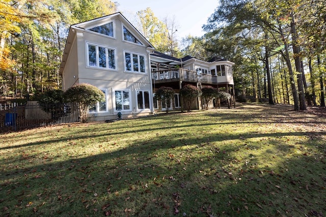 back of property with a deck, a yard, and fence