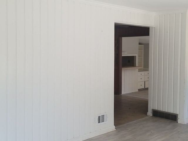 empty room featuring light wood-type flooring, ornamental molding, and wood walls