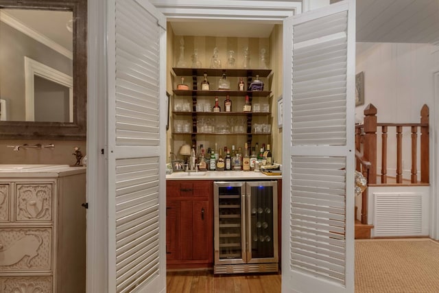 bar with a dry bar, beverage cooler, visible vents, ornamental molding, and a sink