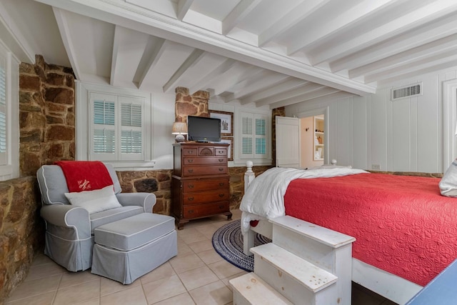 bedroom featuring light tile patterned floors, beamed ceiling, and visible vents