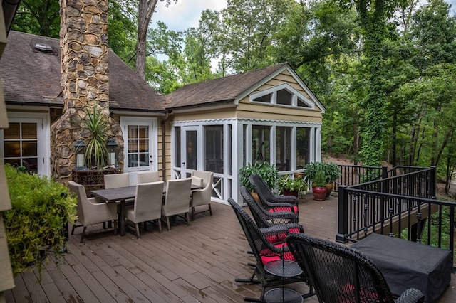 wooden deck with outdoor dining area, area for grilling, and a sunroom