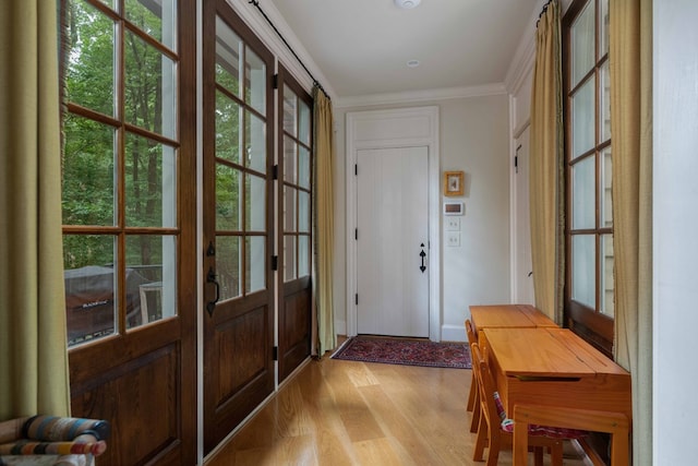 doorway with ornamental molding and light wood-type flooring