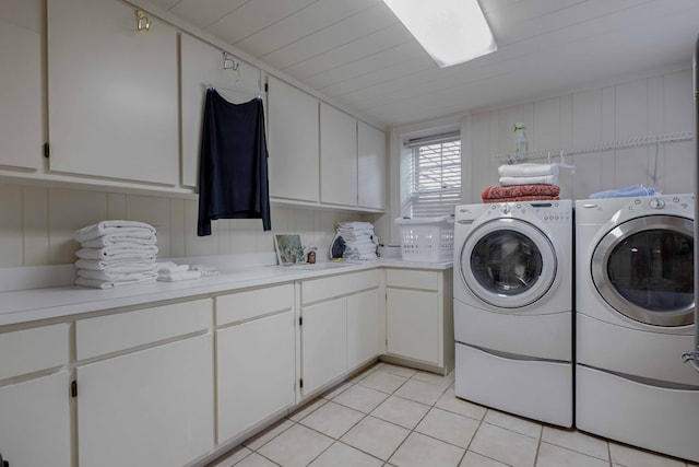 clothes washing area featuring cabinet space, washing machine and dryer, a sink, and light tile patterned flooring