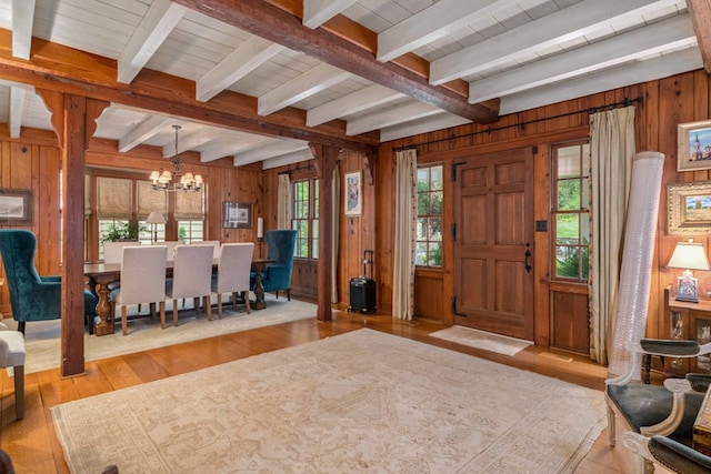 foyer entrance featuring a chandelier, beamed ceiling, wooden walls, and hardwood / wood-style floors