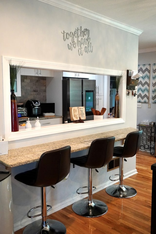 404 19th Ave, Phenix City, AL 36869 - bar area featuring freestanding refrigerator, ornamental molding, and wood finished floors