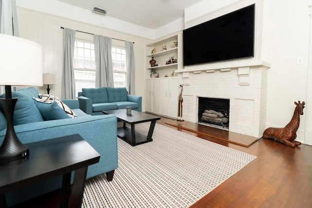 1240 Peacock Ave, Columbus, GA 31906 - living room with wood finished floors, a brick fireplace, and built in shelves