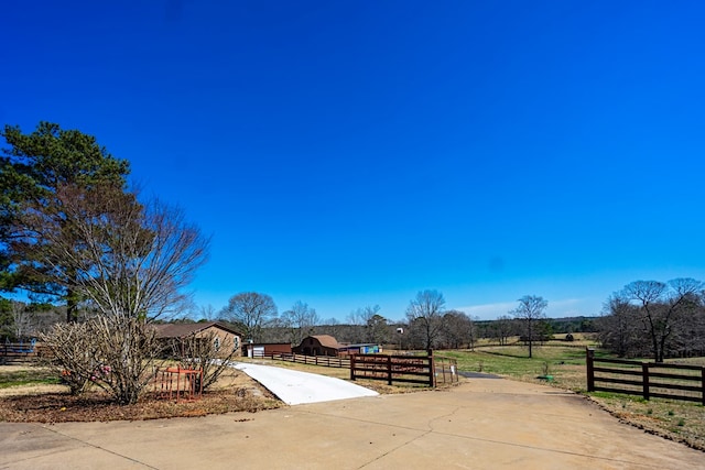 view of patio with a rural view, driveway, and a fenced front yard