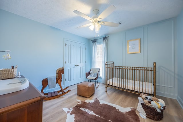 3022 Thornberry Cir, Phenix City, AL 36867 - bedroom featuring a closet, wood finished floors, a textured ceiling, a ceiling fan, and a nursery area