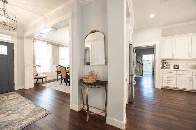 entrance foyer with crown molding, an inviting chandelier, and dark hardwood / wood-style flooring