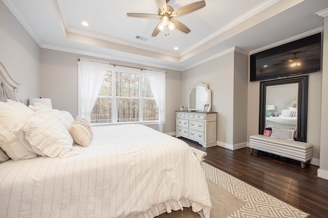 bedroom with crown molding, dark wood-type flooring, ceiling fan, and a tray ceiling