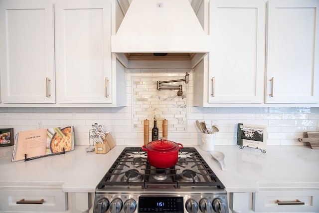 kitchen featuring tasteful backsplash, custom range hood, and white cabinets